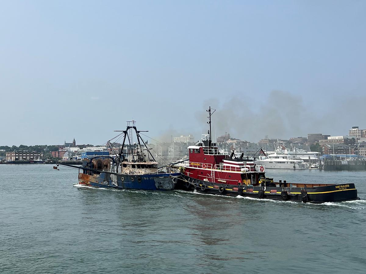 The Nancy McAllister arrives in Portland harbor with the still burning trawler Three Girls