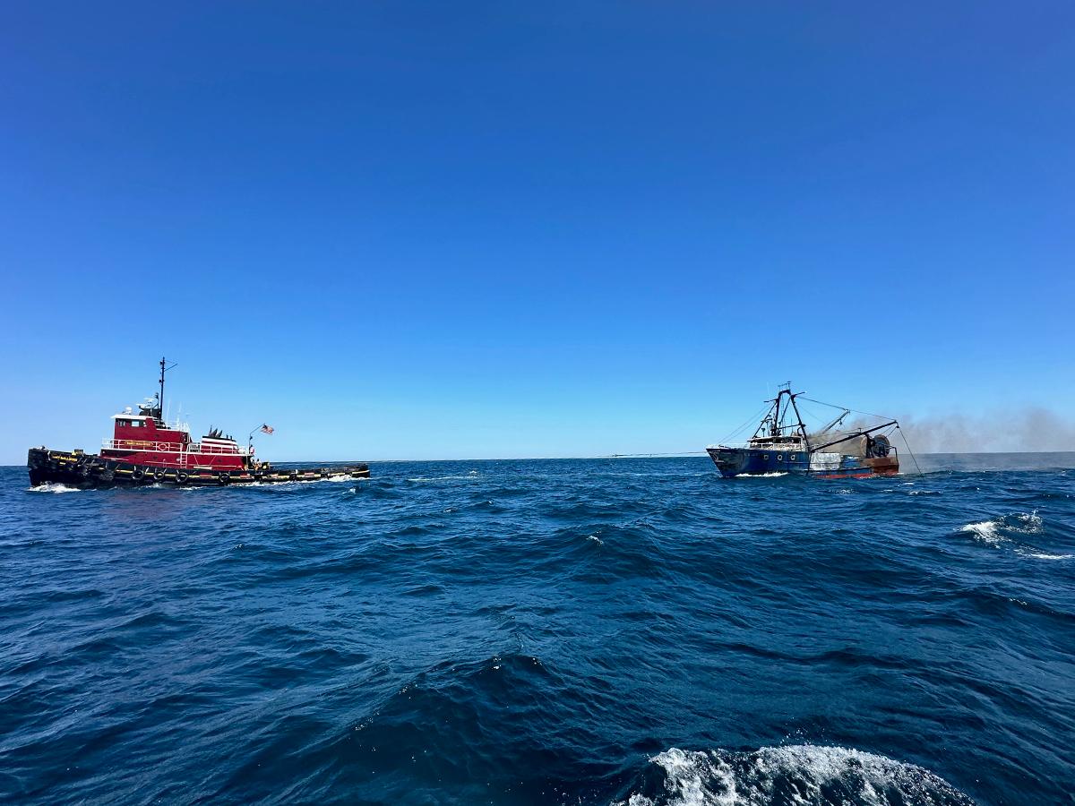 The tug Nancy McAllister tows the burning trawler Three Girls